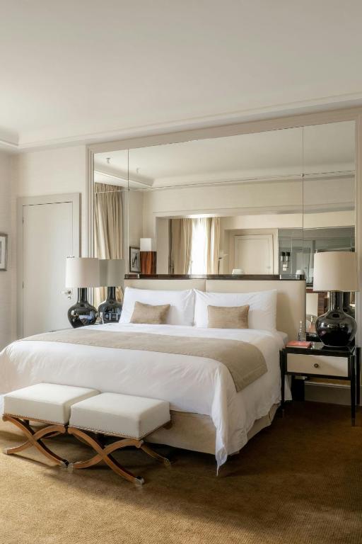 - une chambre avec un grand lit blanc et un grand miroir dans l'établissement Prince de Galles, un hôtel Luxury Collection, Paris, à Paris