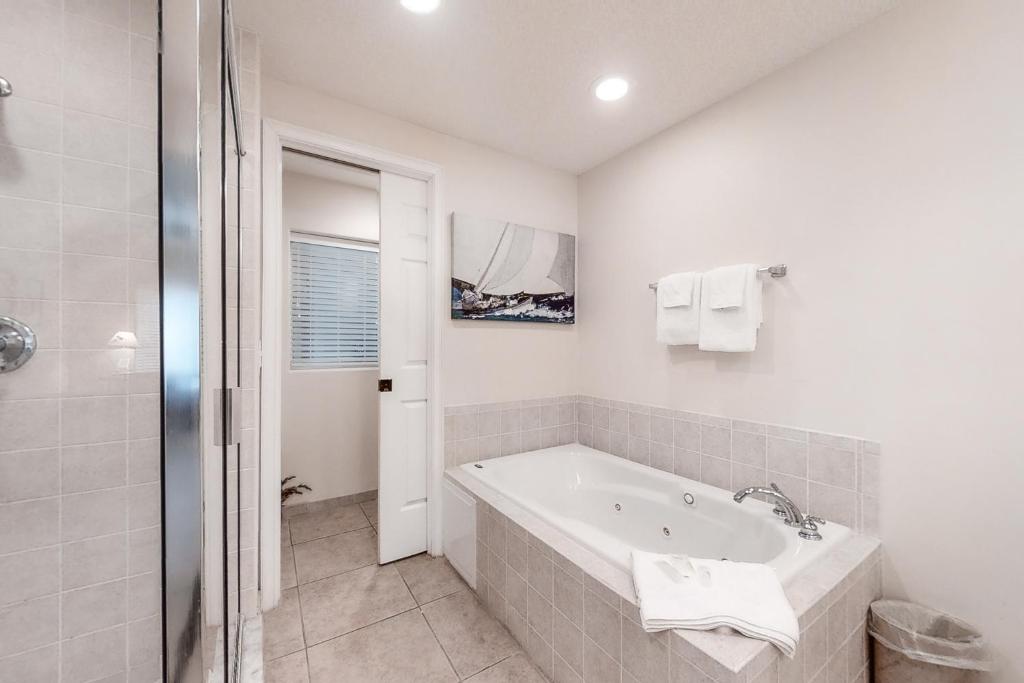 ein weißes Badezimmer mit Badewanne und Dusche in der Unterkunft Wonderful Home Close to Beach w/Shared Pool, Free WiFi, Central AC, W/D in Fernandina Beach