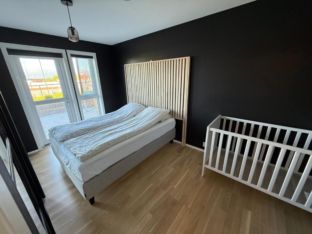 a bedroom with a bed and a window and a crib at Luksuriøs enebolig, nær Ålesund in Ytterland