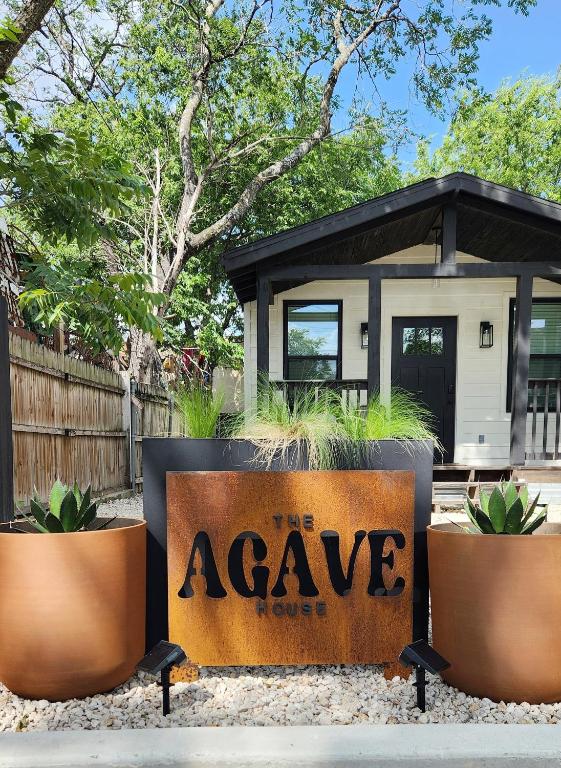 a sign that reads the avenue house in front of three potted plants at Cozy 1BR Tiny Home near Downtown and NB Rivers in New Braunfels