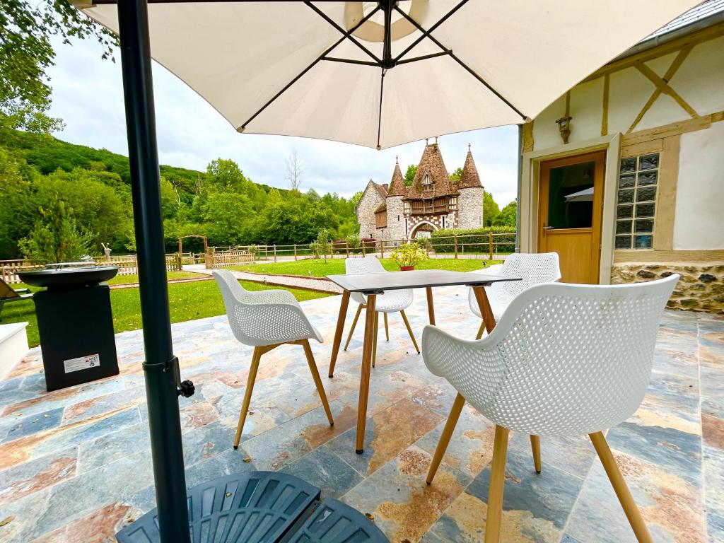 a table and chairs with an umbrella on a patio at Le relais du Château in Fatouville-Grestain