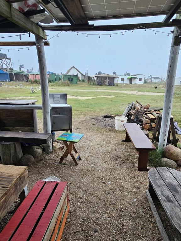 a picnic shelter with benches and a grill in a field at Tiny House in Cabo Polonio