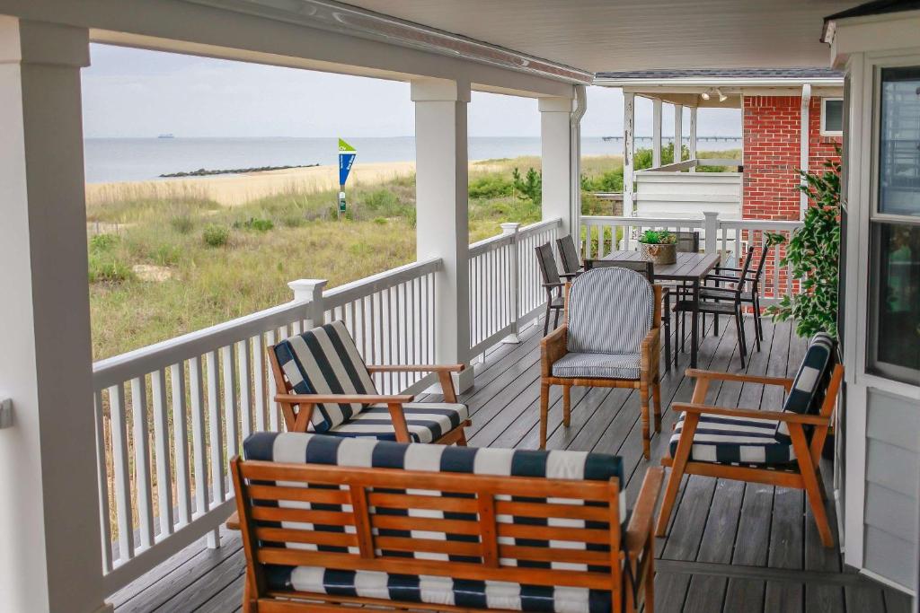eine Veranda mit Stühlen, einem Tisch und Meerblick in der Unterkunft Sojourn Dune Cottage Beach Front Bliss 3 BR 3 BA in Norfolk