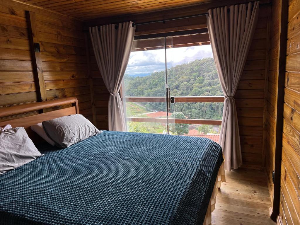 una camera da letto con un letto e una grande finestra di Chalé nas montanhas a Domingos Martins