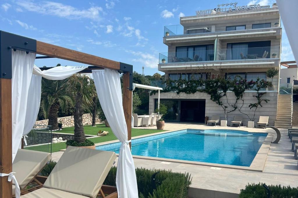 a swimming pool in front of a building at Family-friendly apartments with swimming pool Mandre, Pag - 24196 in Kolan