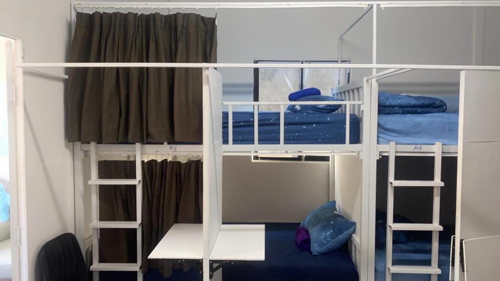 two white bunk beds in a room with a blue couch at Sleepymoon Hostel in Thongsala
