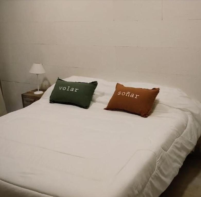 een wit bed met twee kussens erop bij Departamento Divino a tres cuadras de la playa. in Carilo