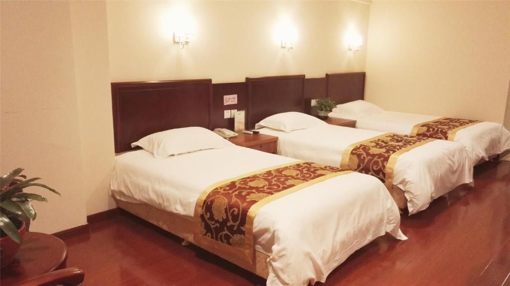 um quarto de hotel com três camas num quarto em GreenTree Inn Hebei Zhangjiakou Bus Station Express Hotel em Zhangjiakou