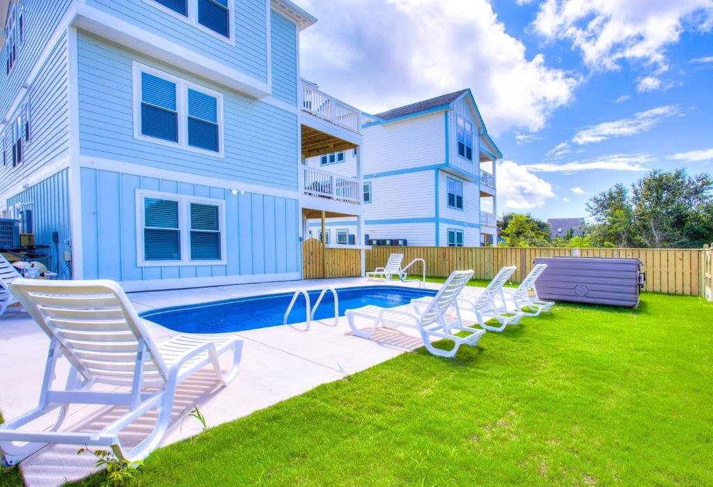 un patio con sillas y una piscina frente a una casa en 4056 - Tight Lines Tan Lines, en Playa de Kitty Hawk