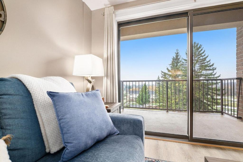 a living room with a blue couch and a large window at Beautiful Lake View Golf Course Condo in Traverse City