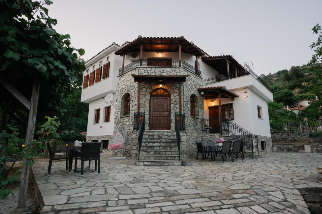 a house with chairs and tables in front of it at Aria Archontiko Pelion in Katochori