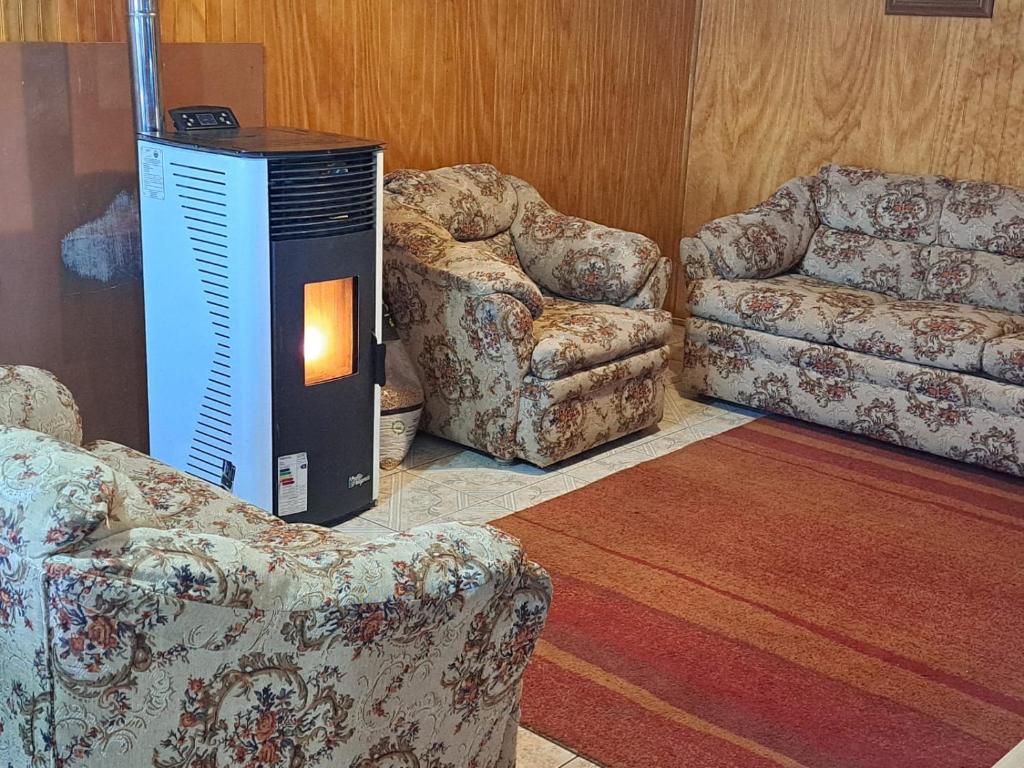 a living room with two chairs and a heater at La chica in Coihaique