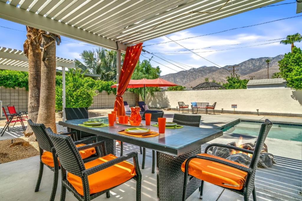 a patio with a table and chairs and a swimming pool at Palm Springs Home with a Resort Style Backyard -Joy pool hot tub views in Palm Springs