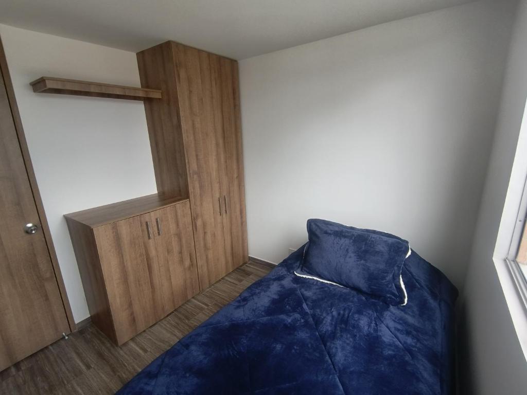 Cómodo Apartamento turístico Paipa في بايبا: غرفة نوم بسرير ازرق وباب خشبي