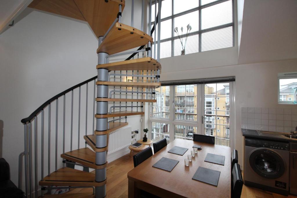 a spiral staircase in a room with a table and chairs at Spacious 3 Bed Apartment in Central Romford just 5 mins to Elizabeth Line for Families Friends and Contractors in Romford