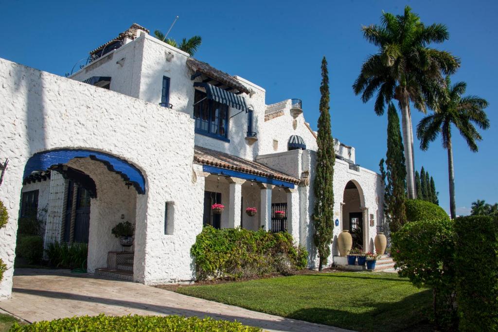 a white house with a palm tree in front of it at Young Mansion Steps To The Beach in Hollywood