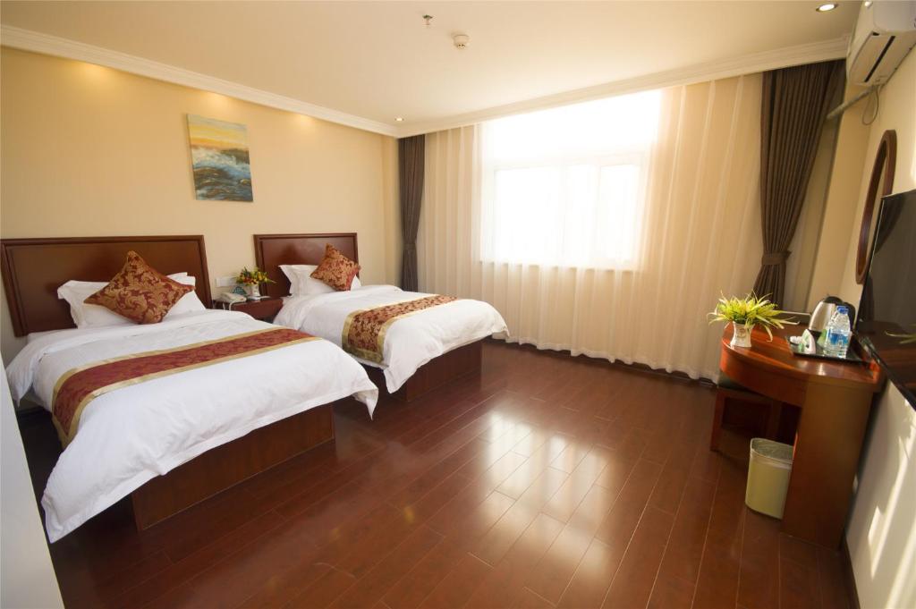 a hotel room with two beds and a window at GreenTree Inn Shandong Jinan Pingyin Industrial Park Express Hotel in Pingyin