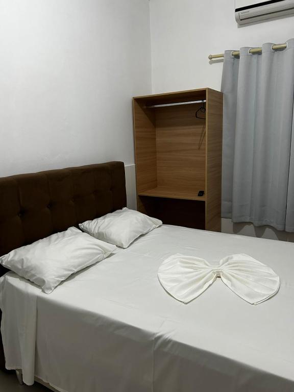 a bed with a white bow on top of it at Pousada Oliveira in Remanso