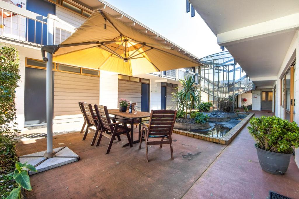 a patio with a table and chairs and an umbrella at Epsom Motel in Auckland