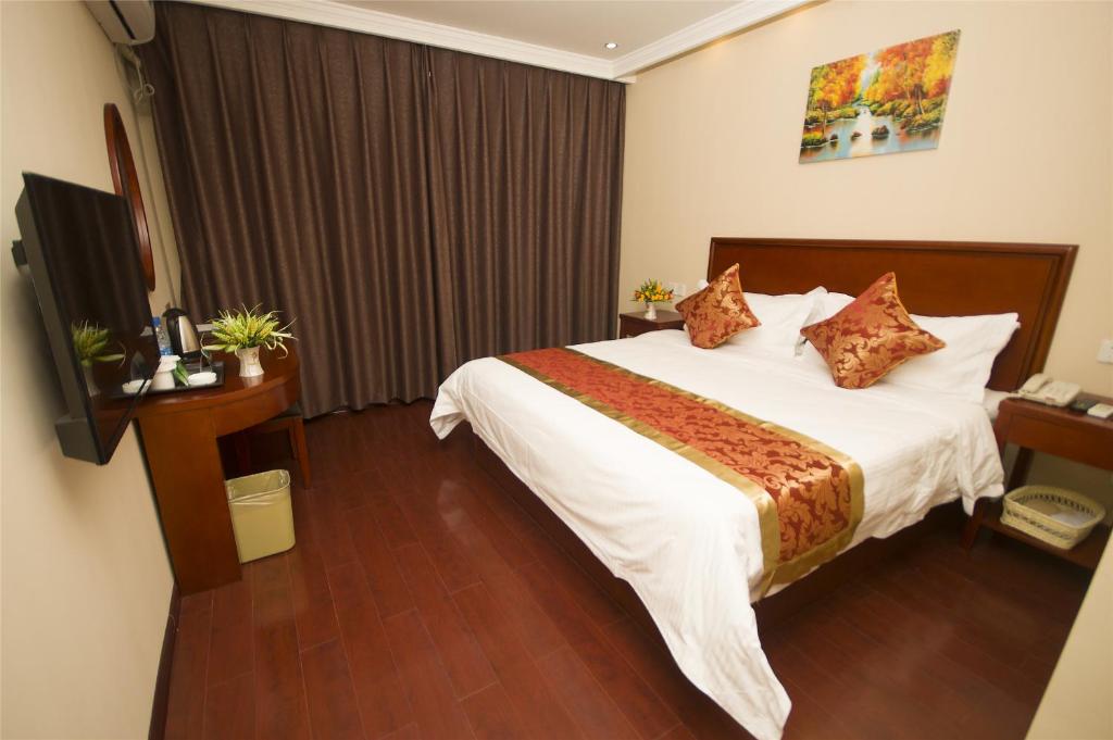 a hotel room with a large bed and a desk at GreenTree Inn JiuJiang Railway Station Business Hotel in Jiujiang