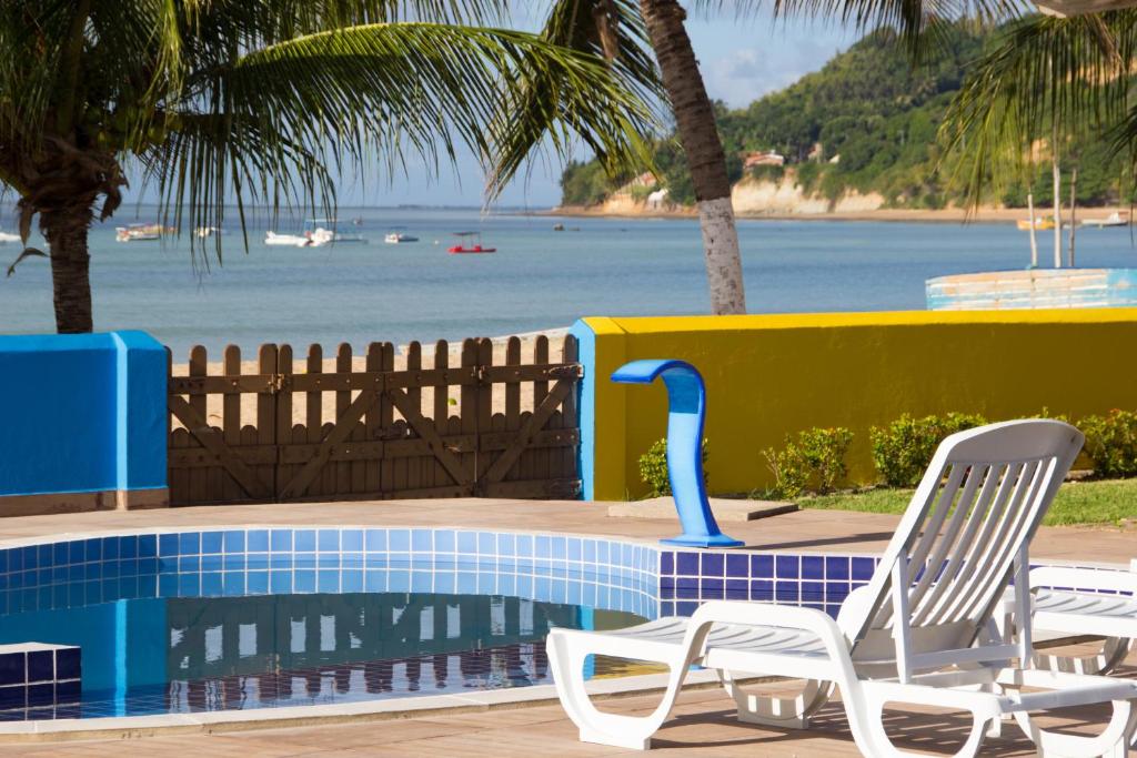 two chairs and a pool with a view of the ocean at Pousada Venezia Tropicale in Japaratinga