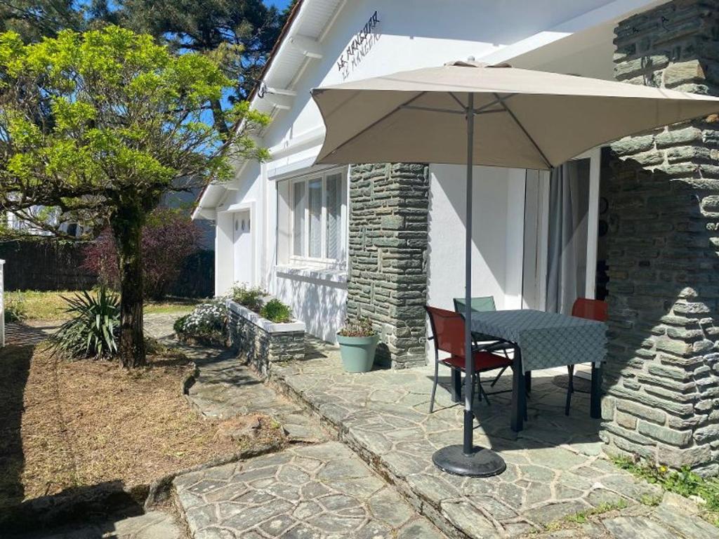 un patio avec une table et un parasol dans l'établissement Maison de Vacances Confortable, Plage à Pied - La Tranche-sur-Mer, 6 Pers., Wifi, Parking, 500m² Terrain - FR-1-22-364, à La Tranche-sur-Mer