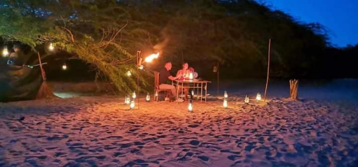 two people sitting at a table on a beach at night at Yala Oruwella Beach Camping & Restaurants in Tissamaharama