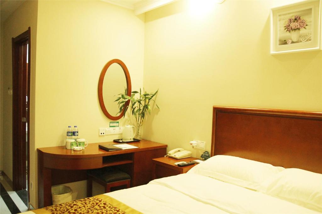 a bedroom with a bed and a desk and a mirror at GreenTree Inn Ji‘nan Shanda Road Business Hotel in Jinan