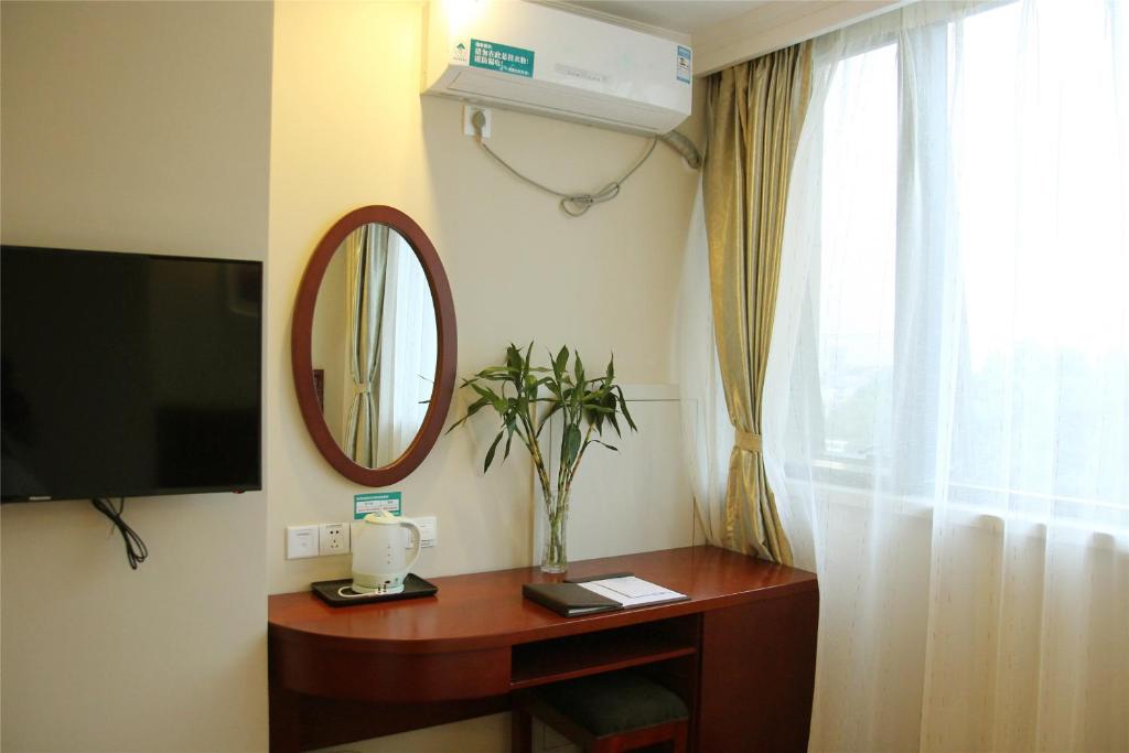 a room with a table with a mirror and a television at GreenTree Inn Ji‘nan Shanda Road Business Hotel in Jinan