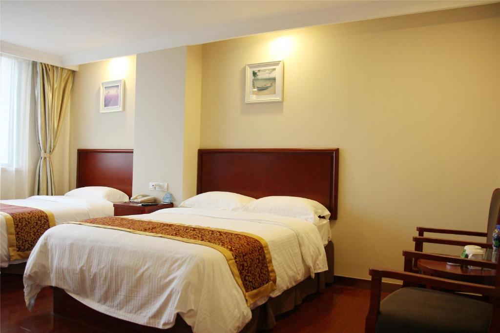 a hotel room with two beds with white sheets at GreenTree Inn Ji‘nan Shanda Road Business Hotel in Jinan