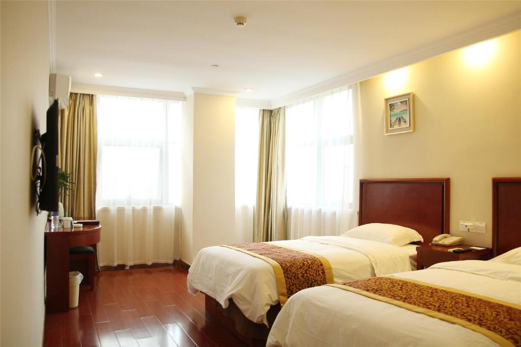 a hotel room with two beds and a window at GreenTree Inn Ji‘nan Shanda Road Business Hotel in Jinan
