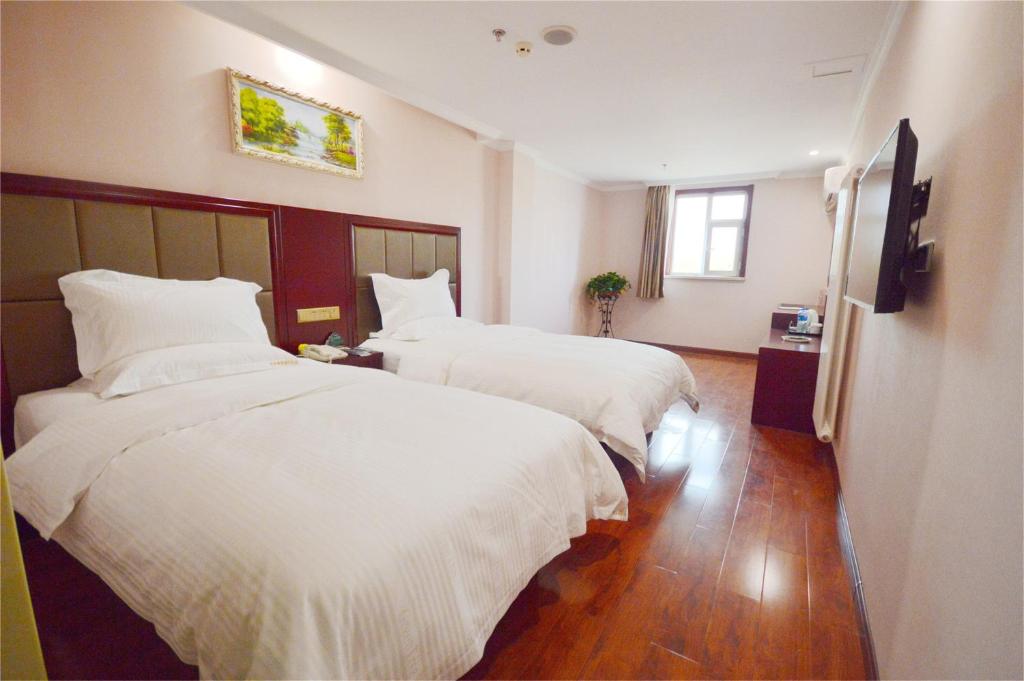 a hotel room with two beds with white sheets at GreenTree Inn Ji‘nan Shanda Road Business Hotel in Jinan