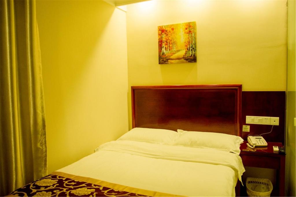 a bedroom with a bed and a phone in it at GreenTree Inn Ji‘nan Shanda Road Business Hotel in Jinan