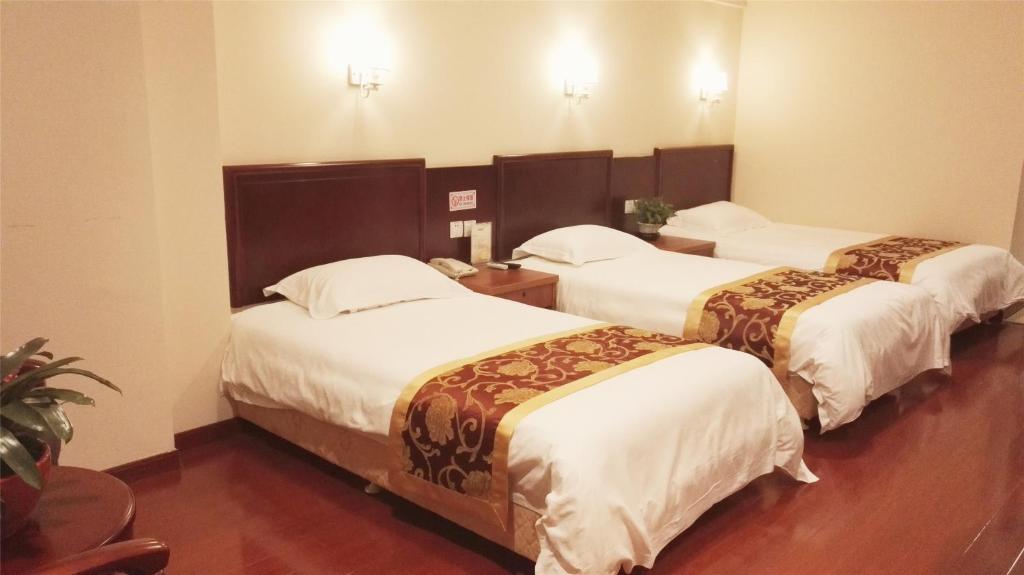 a hotel room with three beds in a room at GreenTree Inn Ji‘nan Shanda Road Business Hotel in Jinan