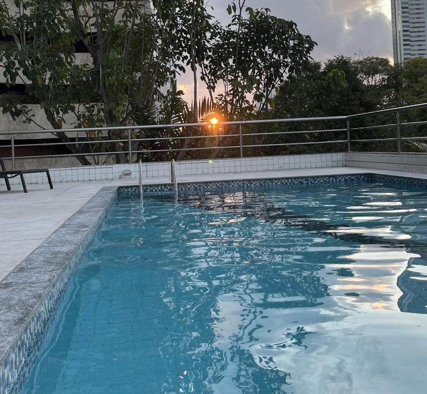 a swimming pool with the sun setting in the background at Flat Parque da Jaqueira in Recife