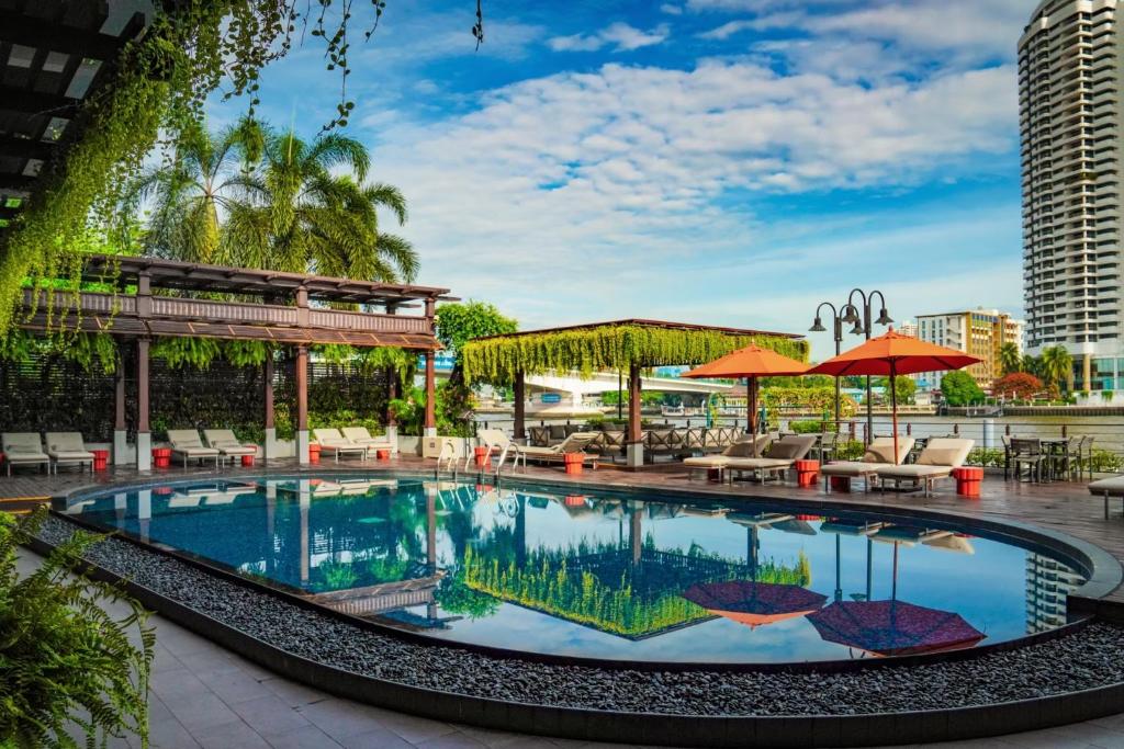 A large outdoor pool surrounded by loungers, umbrellas and tropical landscaping.