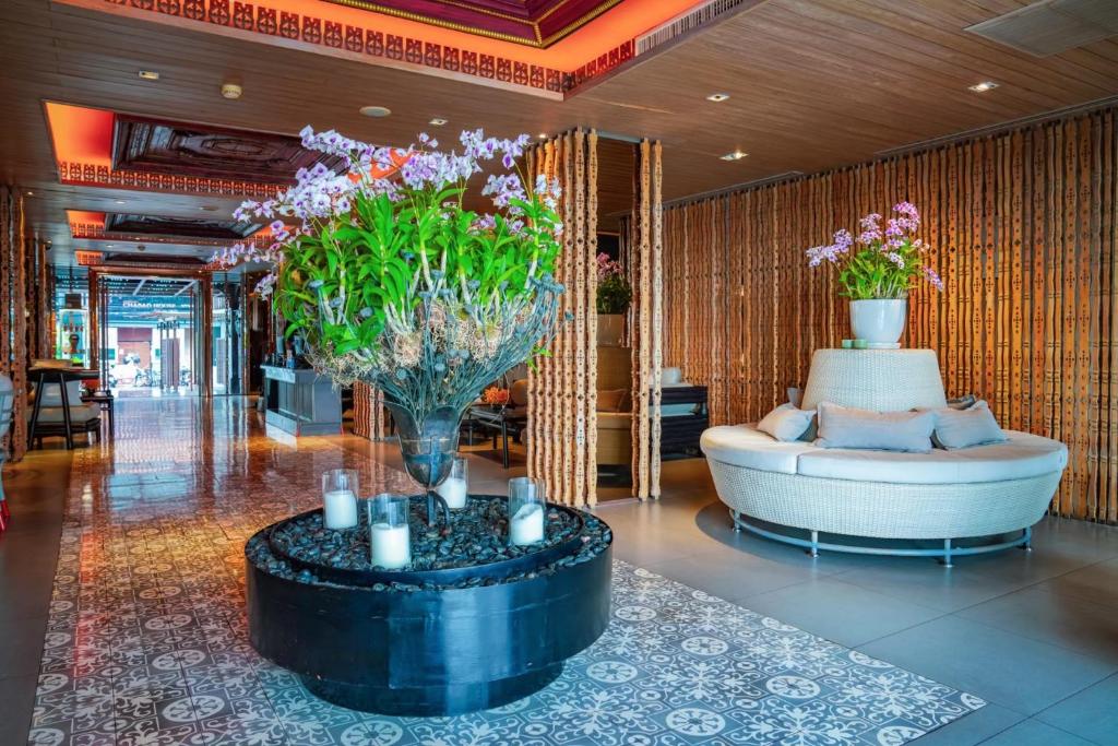 A warmly decorated lobby lounge with a round sofa and flower display.