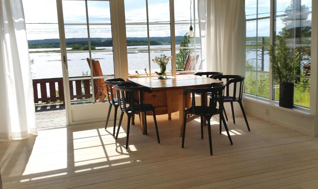 einen Esstisch und Stühle in einem Zimmer mit Fenstern in der Unterkunft Amazing Sea View Luleå in Luleå