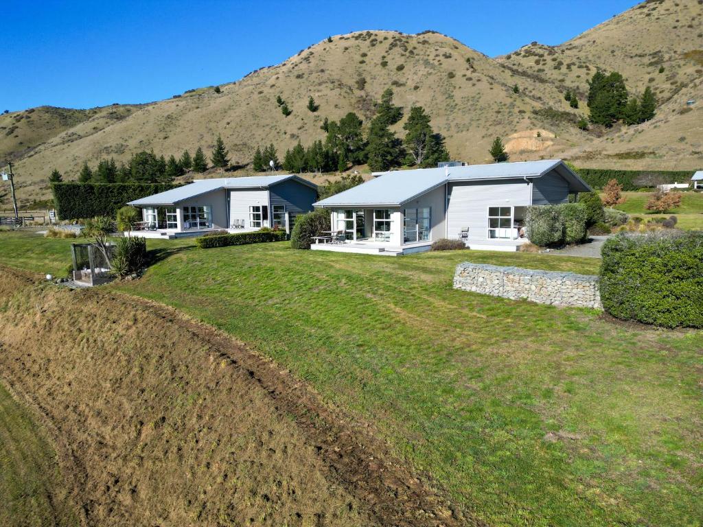 a house in a field with mountains in the background at Hurunui River Retreat - Flax Cottage in Hurunui