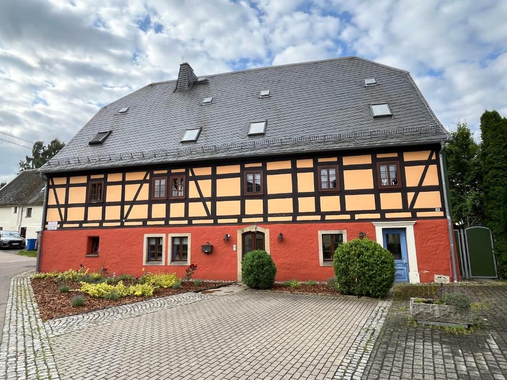 una casa roja y naranja con techo negro en Ferienwohnung im Erzgebirge, en Großhartmannsdorf