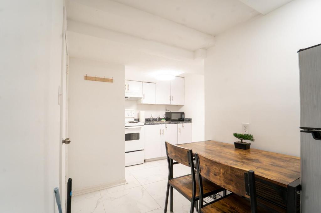 a white kitchen with a wooden table and chairs at Cozy Private 2 bedroom apartment, free Wifi, free parking in heart of Toronto, surrounded by nature in Toronto