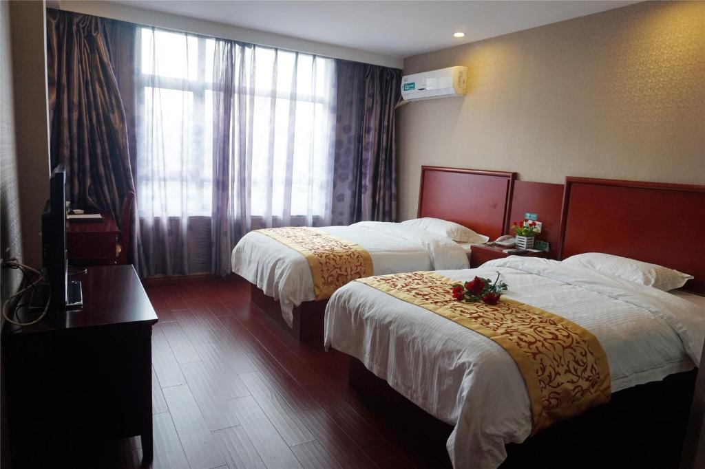 een hotelkamer met 2 bedden en een raam bij GreenTree Inn Huangshan TangKou Beauty Spot South Gate Transfer Center Business Hotel in Huangshan Scenic Area
