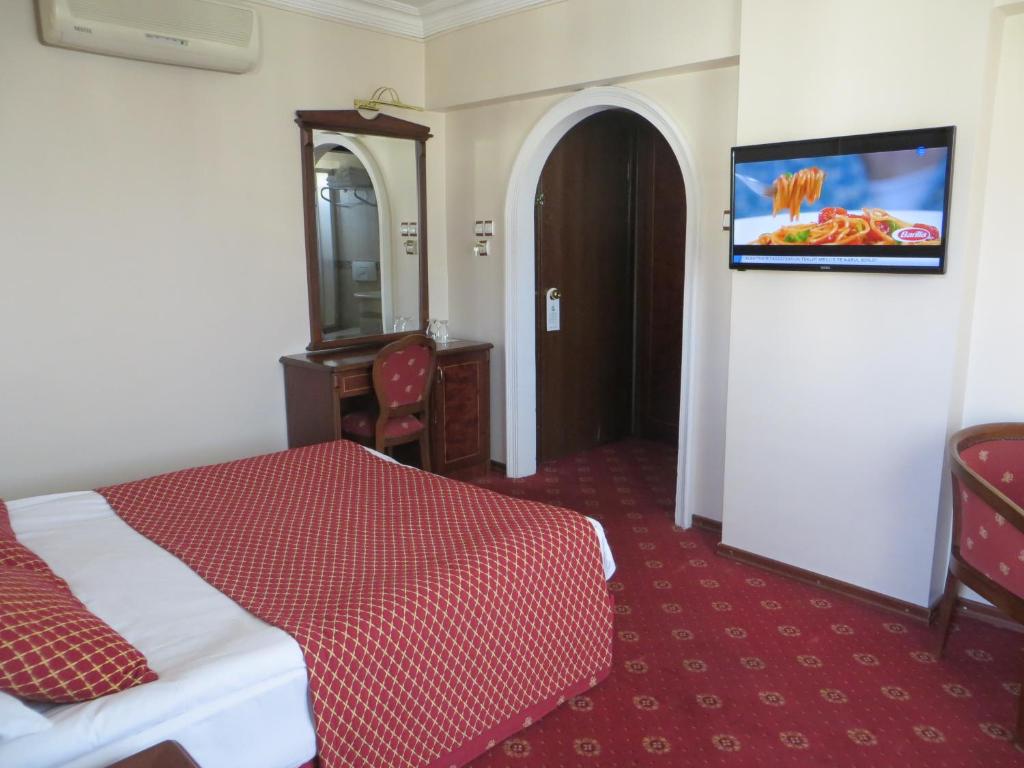 Habitación de hotel con cama y TV en la pared en Ozilhan Hotel, en Ankara