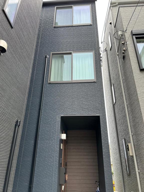 a gray building with a door in front of it at 白樺ハウス女性&家族専用 送迎あり小型犬可 in Chigasaki