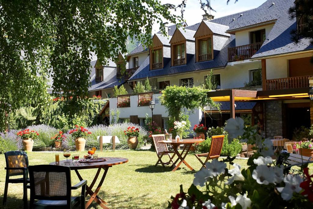 een tuin met tafels en stoelen voor een gebouw bij Hôtel Mir in Saint-Lary-Soulan