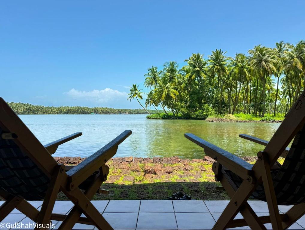 two chairs sitting in front of a body of water at The Oyster Opera in Trikarpur