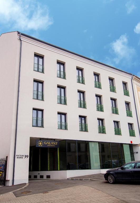 a white building with a car parked in front of it at Galant Apartments in Cluj-Napoca