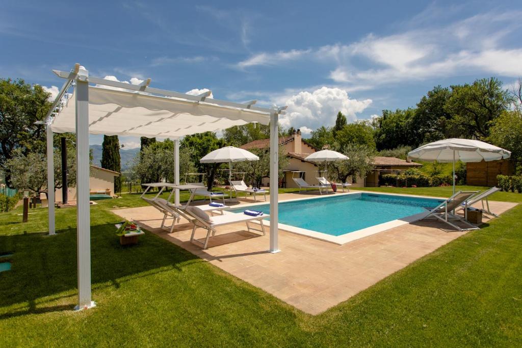 a swimming pool with umbrellas in a yard at LA COLLINA DEGLI ULIVI 8&2, Emma Villas in Montefalco