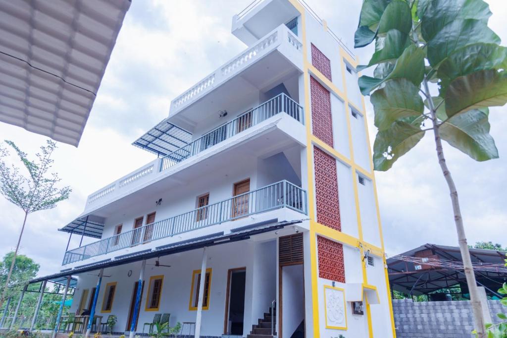 a white building with a palm tree in front of it at Auro Ocean View Residency in Pondicherry
