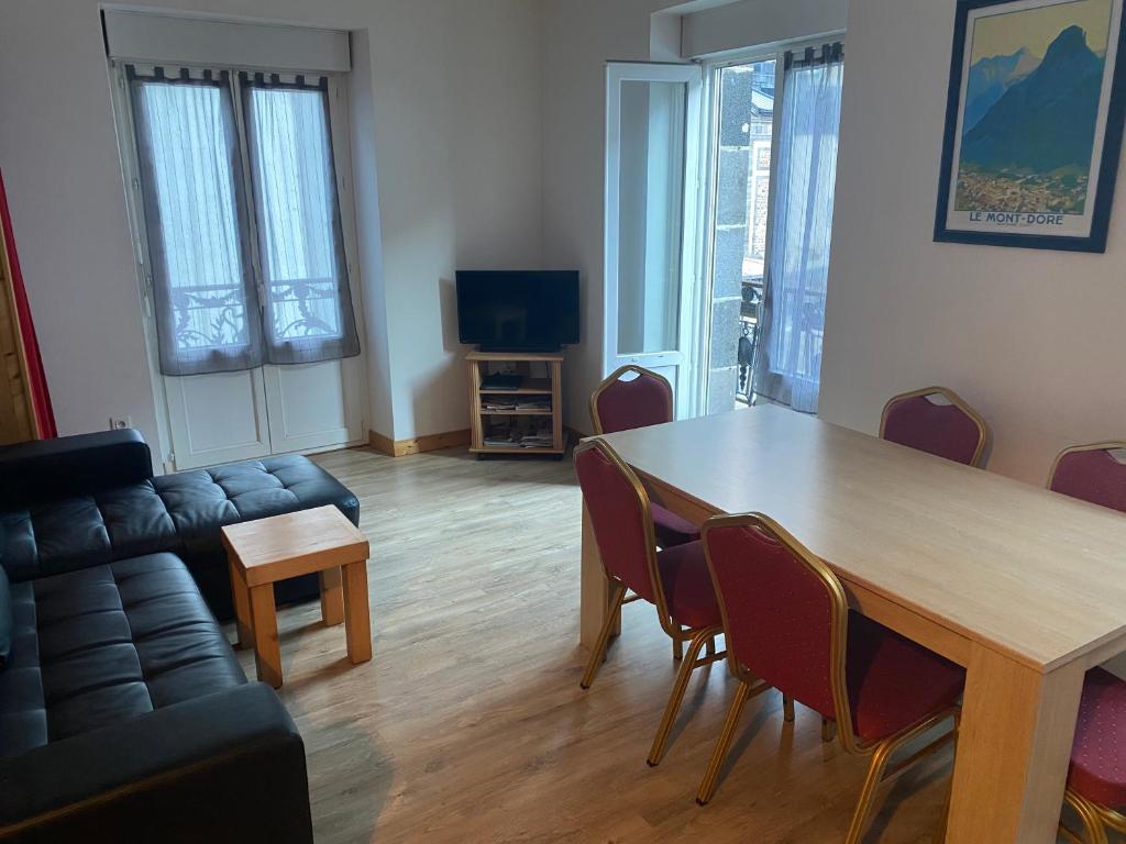 een woonkamer met een tafel, stoelen en een bank bij Val-locations thermes 5 in Le Mont-Dore